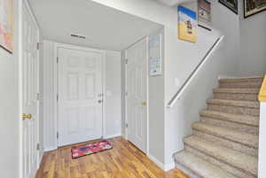 Entrance foyer with stairs, wood finished floors, visible vents, and baseboards