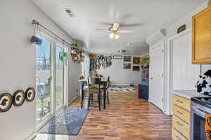 Kitchen with light countertops, visible vents, a ceiling fan, wood finished floors, and baseboards