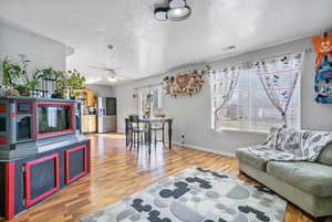 Living area featuring a textured ceiling, visible vents, and wood finished floors
