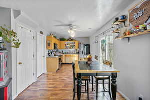 Dining room featuring light wood-style floors, a textured ceiling, baseboards, and a ceiling fan