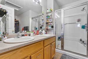 Full bathroom featuring double vanity, a stall shower, a sink, and tile patterned floors