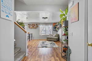 Interior space featuring stairs, a textured ceiling, baseboards, and wood finished floors