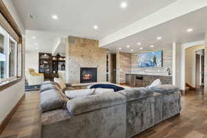 Living room featuring arched walkways, recessed lighting, a large fireplace, wood finished floors, and visible vents