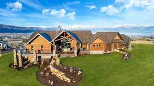 View of front of house featuring stone siding, a mountain view, and a front lawn