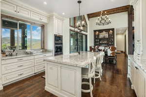 Kitchen with appliances with stainless steel finishes, a kitchen island with sink, a mountain view, a sink, and light stone countertops