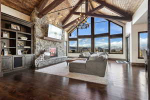 Living area featuring wooden ceiling, a notable chandelier, a fireplace, baseboards, and dark wood finished floors