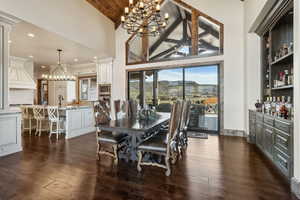 Dining area featuring dark wood-type flooring, wood ceiling, high vaulted ceiling, and an inviting chandelier