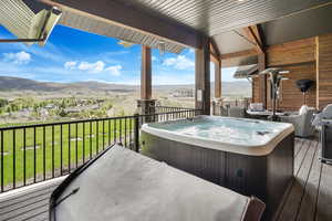 Wooden deck featuring a yard, a mountain view, and a hot tub