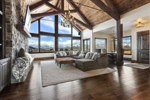 Living room with high vaulted ceiling, wooden ceiling, a notable chandelier, dark wood-style flooring, and beam ceiling