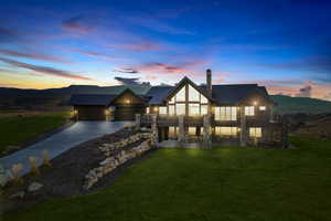 View of front of home with a yard, stone siding, a mountain view, and driveway