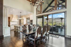 Dining area featuring high vaulted ceiling, a mountain view, dark wood-type flooring, beamed ceiling, and an inviting chandelier