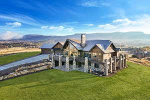 View of front of property featuring concrete driveway, stone siding, a chimney, a mountain view, and a front yard