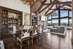 Dining room with dark wood-style floors, a notable chandelier, wood ceiling, high vaulted ceiling, and beamed ceiling