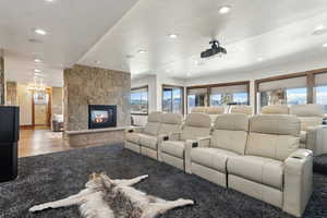 Cinema room with recessed lighting, a stone fireplace, and light wood-style flooring