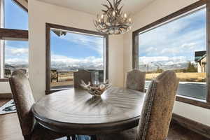 Dining area with a healthy amount of sunlight, a mountain view, a chandelier, and dark wood-style flooring