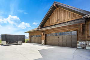 View of home's exterior with board and batten siding, a standing seam roof, metal roof, a garage, and stone siding