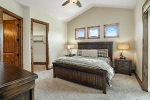 Bedroom featuring a walk in closet, lofted ceiling, light carpet, ceiling fan, and baseboards