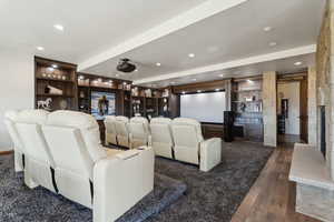 Cinema room featuring built in features, a fireplace with raised hearth, dark wood-type flooring, and recessed lighting