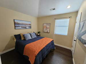 Bedroom with baseboards, a textured ceiling, visible vents, and dark wood-type flooring