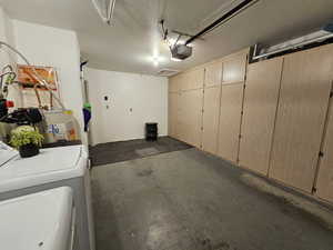 Garage featuring water heater, washer and clothes dryer, and a garage door opener