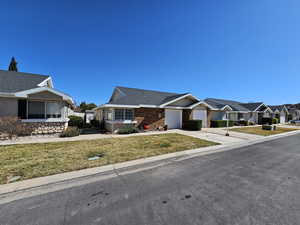 View of front of property with an attached garage, brick siding, driveway, a residential view, and a front yard