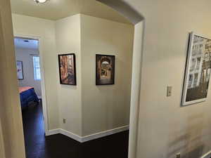 Corridor featuring dark wood finished floors, a textured ceiling, and baseboards