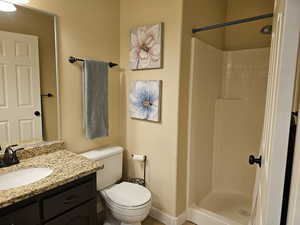 Full bathroom with toilet, a shower stall, and vanity