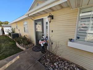 View of exterior entry with central AC unit and a patio