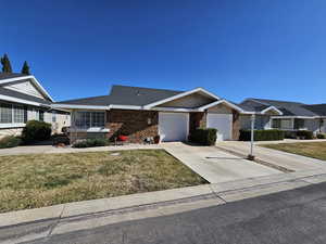 View of front of property featuring brick siding, a shingled roof, an attached garage, a front yard, and driveway