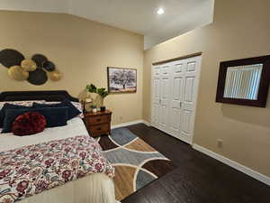 Bedroom with baseboards, dark wood-style floors, vaulted ceiling, a closet, and recessed lighting