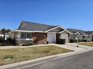 View of front of house with an attached garage, driveway, a front lawn, and brick siding