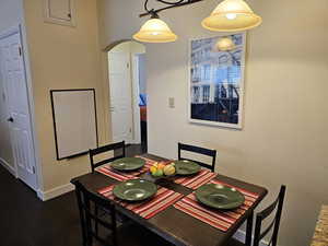 Dining area with dark wood-style floors, arched walkways, and baseboards