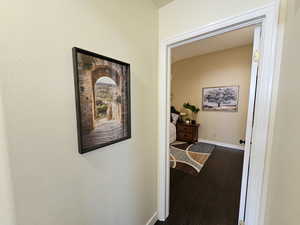 Corridor featuring vaulted ceiling, hardwood / wood-style flooring, and baseboards