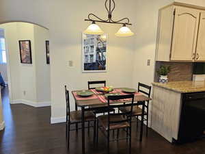 Dining room featuring dark wood-style floors, arched walkways, and baseboards