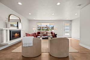 Living room featuring recessed lighting, visible vents, a high end fireplace, wood finished floors, and baseboards