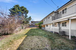 View of yard featuring fence, a balcony, and central AC unit