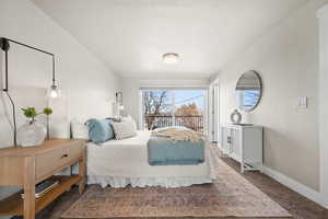 Bedroom featuring access to exterior, baseboards, and dark carpet