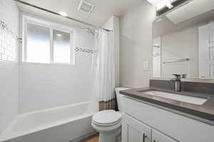 Full bath featuring toilet, shower / bath combo, vanity, and visible vents