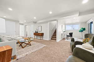 Living area with light carpet, stairs, baseboards, and recessed lighting