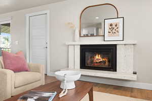 Living room with a fireplace, baseboards, and wood finished floors