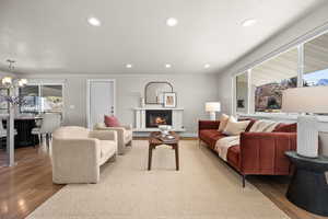 Living room with a chandelier, light wood-type flooring, a glass covered fireplace, and recessed lighting