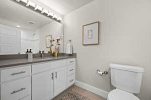 Full bathroom with baseboards, visible vents, toilet, wood finished floors, and vanity