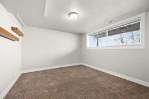 Carpeted empty room with visible vents, a textured ceiling, and baseboards