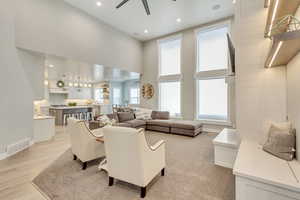 Living room featuring recessed lighting, a high ceiling, visible vents, baseboards, and light wood-type flooring