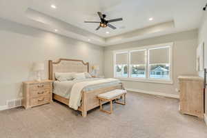 Bedroom featuring a raised ceiling, visible vents, and baseboards