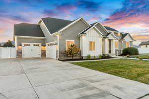 View of front of house featuring a yard, an attached garage, board and batten siding, fence, and driveway