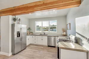 Kitchen featuring white cabinets, appliances with stainless steel finishes, light wood-style floors, a sink, and recessed lighting