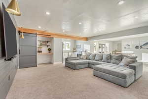 Living room with recessed lighting, carpet flooring, and a barn door