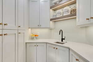 Kitchen featuring white cabinets, a sink, and open shelves