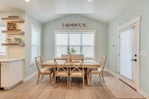 Dining space with light wood-style floors, lofted ceiling, and baseboards